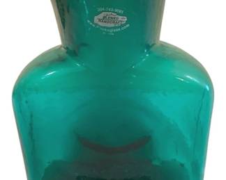 398 - Blenko Emerald Green Water Bottle 6.5"x8" (Description): Blenko handcrafted in a distinctive double  spout water bottle design. This American-made  art glass piece features Blenko's signature  craftsmanship and original sticker. Measures  6.5" x 8".