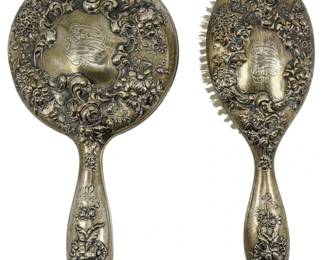 182 - Simpson Hall Miller & Co. Sterling Set (Description): A sterling silver mirror and brush set by  Simpson Hall Miller & Co. The set features  ornate repousse floral decoration on both  pieces. The brush retains its original  bristles. Total weight 17.89 oz.