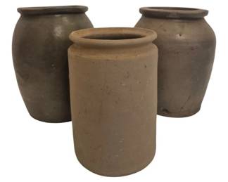 2718 - Three Antique Stoneware Crocks As Is (Description): A collection of three antique stoneware  crocks sold as is. The grouping includes two  matching dark glazed crocks with rolled rims  and bulbous forms, along with one tan  cylindrical crock with a simple rolled lip. These utilitarian vessels show  age-appropriate wear consistent with their  vintage origins.