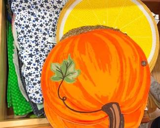 916 - Drawer Lot Assorted Decorative Place Mats (Description): A drawer lot of assorted decorative place  mats featuring a variety of seasonal and  novelty designs. Collection includes a  pumpkin-shaped place mat with leaf detail, a  yellow lemon slice design, floral printed mats, and additional styles in various colors  and patterns.
