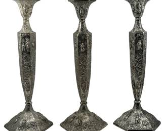 728 - 3 Barbour Silver Plate Candlesticks (Description): A set of three Barbour silver plate  candlesticks. Each candlestick features  ornate repousse decoration with figural  panels on the hexagonal stems and scrollwork  throughout. The candlesticks rest on matching hexagonal bases with flared tops to hold  candles.