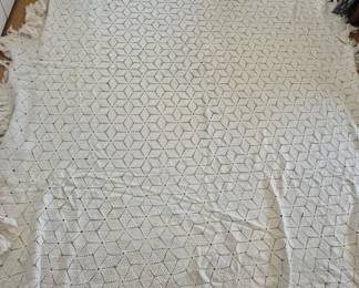 1314 - Vtg Handmade Crochet Lace Bedspread (Description): Features a geometric cube or star pattern  throughout in cream or off-white cotton  thread. The edges display a scalloped border  with fringe detailing on some sides. Shows  signs of age and use consistent with vintage handcrafted linens. Measures 104 x 84