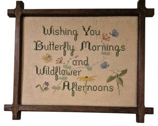 3753 - Needlepoint in Criss Cross Frame 14"x17" (Description): A charming cross-stitch embroidered sign  featuring the phrase "Wishing You Butterfly  Mornings and Wildflower Afternoons"  surrounded by colorful floral and butterfly  motifs. The needlework is mounted in a rustic wooden criss cross frame with notched corner  joints.