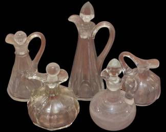 4053 - Group Lot of Vintage Cruets (Description): Group lot of clear glass cruets and  decanters. The collection includes five  pieces of varying sizes and styles, each  featuring elegant handles and decorative  stoppers. The vessels display classic forms suitable for oil, vinegar, or other liquids,  with paneled and rounded body designs.