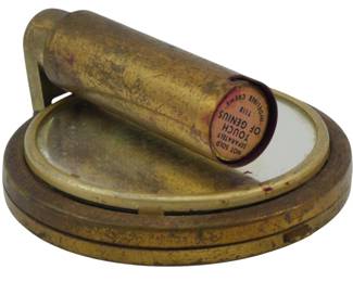 1753 - Touch of Genius Combination Compact w/ (Description): Touch of Genius combination compact with  original lipstick. The brass-toned compact  features a mirrored interior and retains its  original lipstick tube marked "Touch of  Genius" and "Inopilene Creme." Measures 2.5 inches in diameter.