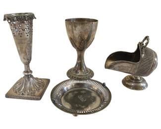 391 - 4 Silver Plated Tableware Items 7.5" (Description): Collection of four silver plated tableware  items. The grouping includes a tall  trumpet-form vase with pierced grape and vine  rim decoration on a square pedestal base, a  footed goblet or chalice with engraved decoration, a round dish with reticulated  border and monogrammed center, and a  miniature coal scuttle form sugar or  condiment server with ribbed body and swing  handle. Largest measures 7.5 inches.