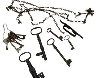 1215 - Group of Antique Skeleton Keys (Description): A collection of antique iron skeleton keys  and decorative chain. The lot includes  several large skeleton keys with oval and  circular bows in various sizes, a ring of  assorted smaller keys, and lengths of decorative iron chain with small keys  attached. The keys display aged patina  consistent with their antique age. Also  included is an iron boot pull or similar  implement.