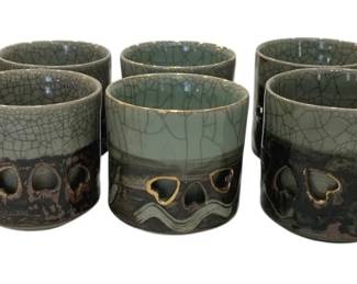 1224 - Japanese Pottery Cups w/ Crackle Glaze 3.5" (Description): Set of ten Japanese pottery cups featuring a  distinctive two-tone design. The upper  portion displays a celadon green crackle  glaze finish, while the lower half features a  dark brown or black glaze with organic cutout patterns revealing the interior. Each  cup measures 3.5 inches. The cups showcase  traditional Japanese ceramic craftsmanship  with their combination of refined crackle  glazing and rustic decorative elements.