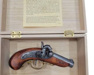 682 - The Gun That Shot Lincoln Replica 2"x7"x4" (Description): Non-firing replica of the gun that shot  Lincoln, presented in a wooden display case  with brass hinges. The case lid interior  features a detailed historical plaque titled  "The Gun That Shot Lincoln" describing the assassination of President Abraham Lincoln on  April 14, 1865. The replica depicts a Baby  Philadelphia Derringer, a single shot  percussion-cap pocket pistol originally  designed in 1850, as used by John Wilkes