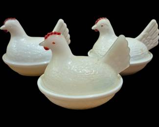 4038 - 3 Milk Glass Hen on Nest Covered Dishes 4"x5" (Description): Three milk glass hen on nest covered dishes.  Each features a white milk glass hen lid with  hand-painted red comb and wattle details,  sitting atop a nest-shaped base. These  classic covered dishes measure 4 inches by 5 inches each.