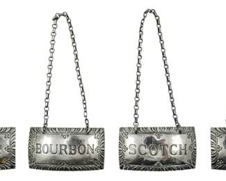 700 - Set of 4 Stieff Sterling Bottle Hangers (Description): Set of four Stieff sterling silver  Williamsburg bottle hangers. Each hanger  features a decorative tag suspended from a  chain, labeled for Vodka, Bourbon, Scotch,  and Gin. Total weight 2.02 oz.