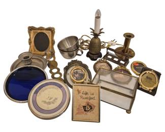 2746 - Group Vintage Metal Frames Candleholders Etc (Description): A group of vintage metal frames,  candleholders, and decorative items. The  collection includes ornate gold-toned picture  frames in various sizes, a brass pineapple  accent lamp, a glass and brass jewelry casket, a blue enamel round frame, stainless  steel baby cup, brass candlestick holder, and  small framed decorative pieces including a  cross-stitch cat sampler reading "Life is  Purrfect."
