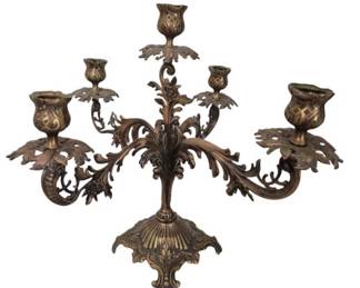 1282 - Ornate Brass 5-Arm Candelabra 12"x19" (Description): Ornate brass five-arm candelabra featuring  elaborate Baroque-style foliate scrollwork  and acanthus leaf detailing throughout. The  piece displays four curved arms extending  from a central stem, each terminating in decorative tulip-form candle cups with  pierced leaf-shaped bobeches. The central  fifth arm rises above the others. The  candelabra rests on an ornamental shell-form  base with detailed repousse work. The brass