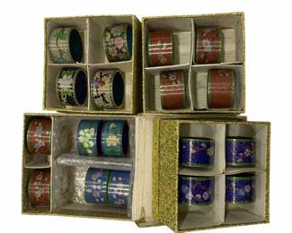 675 - Collection Cloisonne Napkin Holders (Description): Presented in their original decorative boxes.  The napkin holders feature various colorful  enamel designs with floral and geometric  patterns in shades of blue, teal, coral, and  pink with gilt accents.