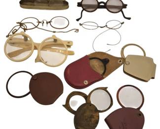 2736 - Group Antique Spectacles & Magnifying Lenses (Description): A collection of antique spectacles and  magnifying lenses. The group includes several  pairs of vintage eyeglasses in various  styles, including round wire-rimmed  spectacles with folding temples, bone or celluloid folding spectacles, and dark-lensed  glasses. Also included are multiple pocket  magnifying glasses with leather cases and  covers in burgundy, brown, and tan. One pair  of spectacles comes with its original metal
