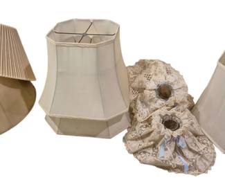 4021 - Group of Assorted Vintage Lamp Shades (Description): A group of lamp shades in various styles and  sizes. The collection includes a pleated  shade with curved bottom edge, two cut-corner  rectangular shades with white fabric, and a  pair of decorative lace-covered shades with ribbon accents in cream and ivory tones.  Suitable for table lamps or bedroom lighting.