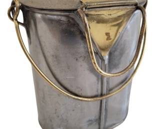 440 - Vtg Metal Canister w/ Lid & Bail Handle (Description): Vintage metal canister featuring a fitted lid  with bail handle closure. The cylindrical  container has a utilitarian design with  brass-tone hardware including ring  attachments for the swing handle. Shows aged patina consistent with use. Measures 10"