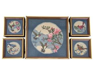 1315 - Framed Needlepoint Bird & Floral Panel Set (Description): Set of five framed needlepoint panels  featuring birds and floral motifs. The  collection includes one large central piece  depicting hummingbirds among pink blossoms,  accompanied by four smaller coordinating panels showing various songbirds with  flowering branches. Each piece features a  circular design on a blue ground, mounted in  matching gilt-tone frames. Largest measures  13"x13".
