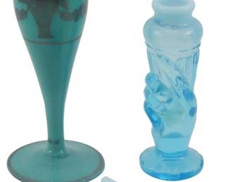 865 - 2 Vtg Perfume Bottles w/ 2 Stoppers Lot (Description): A lot of two vintage perfume bottles  accompanied by two stoppers. One bottle  features a teal or turquoise colored glass  with decorative overlay, while the other  appears in a lighter blue translucent glass with figural design. Both stoppers are  included.