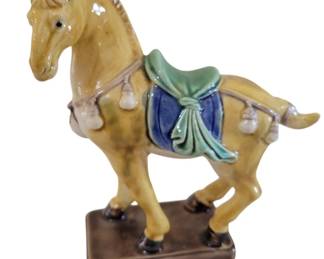 450 - Majolica Tang Style Horse Statue 5"x6" (Description): A majolica horse statue in the Tang dynasty  style. The ceramic figure features a  traditional sancai-style glaze with a  golden-yellow horse adorned with a blue and  green saddle blanket, decorative tassels, and detailed harness work. The prancing horse  stands on a rectangular brown base. Measures  5 inches by 6 inches.
