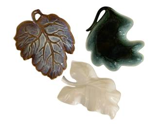 592 - 3 Hull Pottery & Etc Leaf Dishes 13"x10" (Description): Three leaf-shaped dishes in assorted glazes.  The collection includes a purple-brown grape  leaf dish, a dark green leaf dish with curved  stem handle, and a cream-colored leaf dish.  Largest measures 13 inches by 10 inches.
