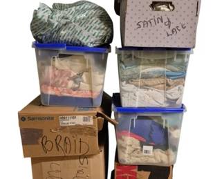 4098 - 11 Containers Full of Assorted Fabric (Description): Collection of eleven containers full of  fabric. The assortment includes various types  of fabric stored in plastic bins and  cardboard boxes, with labels indicating  contents such as satin, lace, braid, and velvet. A substantial quantity suitable for  sewing, crafting, or textile projects.