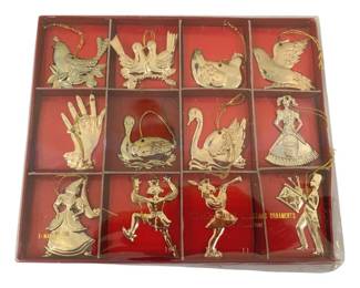 355 - Vtg 12 Days of Christmas Metal Ornaments (Description): Vintage set of 12 Days of Christmas metal  ornaments. Each ornament depicts a different  day from the classic Christmas carol,  featuring gold-tone metal construction with  hanging cords. Presented in original red display box. Measures 9" x 7.5".
