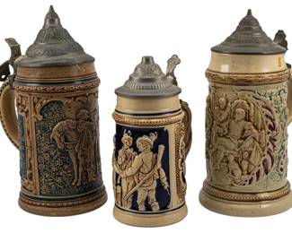 744 - 3 Vintage Steins (1 Broken) Largest: 9" (Description): Collection of three vintage ceramic beer  steins with pewter lids, featuring relief  decorations. One stein is broken. The largest  measures 9 inches tall.