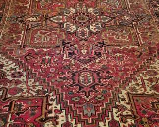 3733 - Persian Heriz Rug 138"x114" (Description): Persian Heriz rug featuring a traditional  geometric medallion design in rich tones of  red, navy blue, cream, and touches of pink  and teal. The central field displays the  characteristic bold angular medallion pattern typical of Heriz weavings, surrounded by  complementary corner spandrels and an  intricate multi-band border. Measures 138  inches by 114 inches.