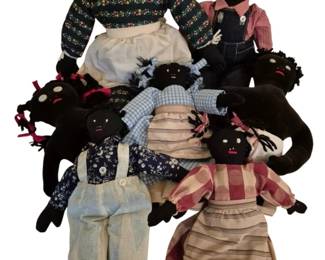 4172 - Group Lot of Handmade Black Cloth Dolls (Description): Group lot of handmade cloth dolls featuring  black fabric construction. The collection  includes multiple dolls of varying sizes  dressed in vintage-style clothing including  gingham, floral prints, overalls, and period dresses with aprons. The dolls feature yarn  or fabric hair, embroidered or button eyes,  and hand-stitched details. The clothing  styles suggest folk art or traditional  Southern American craftsmanship.