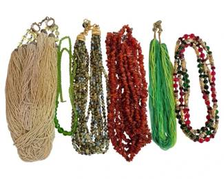 1978 - 6 Vintage Beaded Necklaces (Description): Collection of six vintage necklaces featuring  a variety of beaded designs. The assortment  includes multi-strand seed bead necklaces in  neutral cream and vibrant green tones, a  multi-strand faceted crystal necklace with golden accents, a chunky amber-colored chip  bead necklace, and a colorful multi-strand  necklace with red, green, and gold beads.  Various clasp styles throughout the  collection.