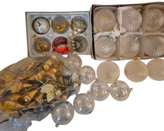4066 - Group of Christmas Ornaments (Description): Group of Christmas ornaments featuring a  variety of styles and finishes. The  collection includes frosted white glass balls  decorated with snowflake designs, clear  iridescent glass ornaments, gold-topped clear glass baubles with decorative motifs, and  assorted metallic gold ornament picks.  Several ornaments remain in their original  boxes, while others are loose or in plastic  bags. The assortment encompasses both