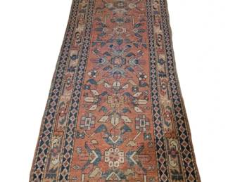 3989 - Antique Persian Heriz Runner Rug 32"x105" (Description): Antique Persian runner rug in the Heriz  style, featuring traditional geometric  medallion motifs on a warm terracotta-red  field. The design includes stylized floral  and bird-like elements in shades of blue, cream, and soft pink. Multiple decorative  borders frame the central field, including a  distinctive navy blue diamond-pattern outer  border. The rug shows age-appropriate wear  consistent with its antique status.