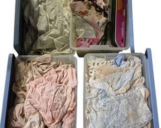 4096 - 4 Small Totes of Vtg Lace, Fabric & Textiles (Description): Collection of four small totes containing  assorted vintage lace, fabric, and textile  items. The lot includes white and  cream-colored lace pieces, pink and  blush-toned fabric items, embroidered textiles, and sewing notions. Various styles  of lace work are represented, including  eyelet and decorative trim pieces. An ideal  lot for crafters, seamstresses, or collectors  of vintage textiles.