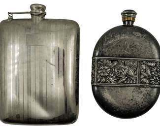 128 - 2 Unmarked Liquor Flasks 7" (Description): Two unmarked flasks. One features a  rectangular form with vertical ribbed design  and hinged cap. The other is oval-shaped with  repousse floral decoration featuring roses  and daisies, with script monogram engraving on the upper portion.