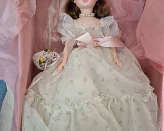 1390 - Madame Alexander Elise Bridesmaid #1665 17" (Description): Elise Bridesmaid doll, model #1665. This  elegant doll features a floral print dress  with lace trim and pink satin accents, a  pearl necklace, and a floral headpiece. She  carries a small wicker basket with flowers. Measures 17 inches tall.