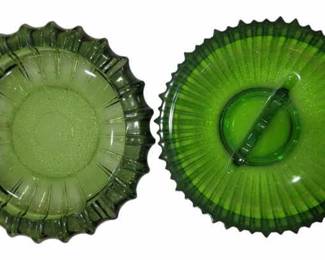 684 - 2 Mid-Century Green Glass Ashtrays (Description): Two green glass ashtrays featuring decorative  ribbed and scalloped edges. One ashtray has  a radial sunburst pattern with a central  cigarette rest.