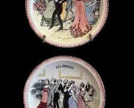 487 - 4 Limoges Plates w/ Wall Hangers 9.5" (Description): A set of four decorative wall hanging plates  featuring "Les Danses" scenes depicting  elegant figures in Victorian-era attire at  social gatherings and dances. One plate is  cracked and sold as is. Each plate measures 9.5 inches in diameter.