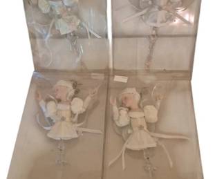 4064 - 4 Kurt Adler Christmas Lady Ornaments Boxed (Description): A set of four Kurt Adler Christmas lady  ornaments, each presented in its original  clear display box. The ornaments feature  elegant female figures dressed in white and  ivory attire with delicate embellishments, posed in graceful ballet-like positions. Each  figure appears to be crafted with  porcelain-style faces and decorative fabric  costumes adorned with ribbons and beading.