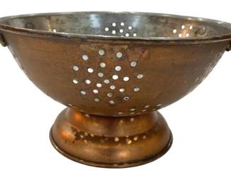 1238 - Vintage Handled Copper Strainer Colander (Description): Vintage copper colander featuring a stainless  steel interior lining. This footed kitchen  piece has a classic pedestal base design with  dual ring handles on either side. The bowl  features a traditional perforated pattern for draining. The exterior displays a warm  copper patina consistent with age and use.