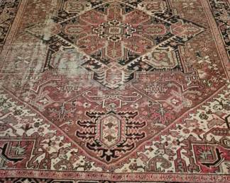 3919 - Antique Persian Heriz Room Size Rug 141 x 110 (Description): Antique Heriz rug featuring a traditional  geometric medallion design in tones of rose,  cream, navy, and coral. The rug displays  classic Heriz styling with a central  diamond-shaped medallion surrounded by angular floral and geometric motifs, framed  by a decorative border. Shows wear spots  consistent with age and use. Measures 141  inches by 110 inches.