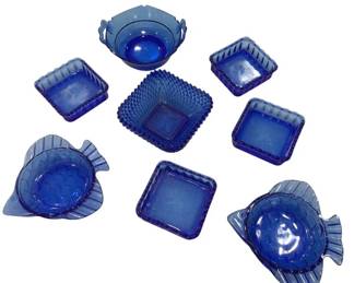 1227 - Assorted Cobalt Blue Glass Decor Pieces (Description): A collection of assorted cobalt blue  glassware decor pieces. The lot includes  various shapes and styles featuring pressed  glass designs, including fish-shaped dishes  with scaled detailing, square plates with sunburst patterns and ribbed edges, a hobnail  pattern container, and decorative bowls. The  pieces showcase different textures and  forms, all unified by their rich cobalt blue  coloring, making them suitable for display or