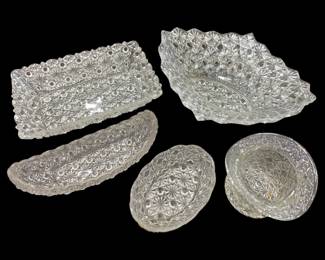 1255 - Button & Bows Pressed Glass Serving Pieces (Description): Collection of five assorted pressed glass  serving pieces in the Button & Bows pattern,  also known as Thousand Eye. The grouping  includes a rectangular dish, a large ruffled  bowl, an elongated celery dish, an oval bowl, and a small round dish. Each piece features  the distinctive hobnail and starburst pattern  characteristic of this popular pressed glass  design. Clear colorless glass throughout.