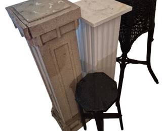 3776 - 4 Plant Stands 40" (Description): Collection of four plant stands measuring 40  inches tall. The grouping includes a painted  wood pedestal with classical paneled design,  a white fluted column-style pedestal with  marble top, a black painted octagonal top side table stand, and a dark wicker basket  planter on a metal tripod base. Various  styles suitable for displaying plants or  decorative objects.