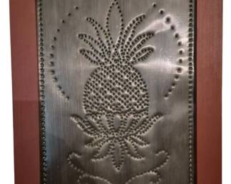 3985 - Pineapple Punch Tin Panel in Wood Frame (Description): Pineapple punch frame featuring a decorative  punched tin panel with a pineapple motif set  within a red-painted wooden frame. The tin  panel displays traditional punch work  technique with a central pineapple design surrounded by a decorative punched border.