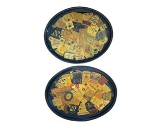 534 - 2 Oval Vtg Trays w/ Liquor Labels Decoupage (Description): Pair of oval vintage trays featuring  decoupage liquor labels. The trays display a  collage of various whiskey, bourbon, and  spirit labels including Wild Turkey, VAT 69,  Smirnoff, Virginia Gentleman, and other brands. Each tray has a dark blue rim  surrounding the label-covered interior.  Measures 28.5" x 24".