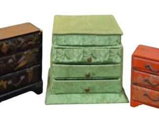 1473 - 3 Oriental Miniature Chest Jewelry Boxes (Description): Three Oriental jewelry boxes designed as  miniature chests of drawers. The collection  includes a black lacquered box with painted  decorative motifs, a green fabric-covered box  with floral pattern and three drawers, and a red lacquered box with traditional Oriental  designs and metal drawer pulls. Each box  features multiple small drawers for storing  jewelry and trinkets.