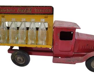 432 - Metalcraft Coca-Cola Delivery Truck 11.5" (Description): Antique Metalcraft Coca-Cola delivery truck  in pressed steel construction. This vintage  toy truck features a red cab and yellow bed  with the classic advertising slogan "Every  Bottle Coca-Cola Sterilized" displayed on the back panel. The truck includes miniature  glass Coca-Cola bottles in the cargo area.  Shows authentic age-related wear consistent  with its vintage status. Measures 11.5" x 4".