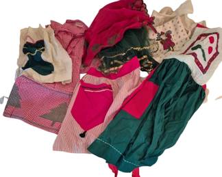 4077 - Group of Vintage Christmas Aprons (Description): Group of vintage Christmas aprons featuring a  variety of festive designs and styles. The  collection includes half aprons and full  aprons in traditional holiday colors of red,  green, and white. Designs feature gingham patterns, holiday motifs including Christmas  trees and candy canes, organza overlays, and  rickrack trim details. A charming assortment  ideal for holiday entertaining or vintage  textile collecting.