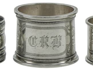 97 - 3 Assorted Makers Sterling Napkin Holders (Description): Three assorted sterling silver napkin holders  from various makers. One features decorative  banding with a floral motif, another  displays an ornate engraved cartouche with  the monogram "C.R.B." surrounded by foliate scrollwork and beaded borders, with the total  weight being 2.78oz.